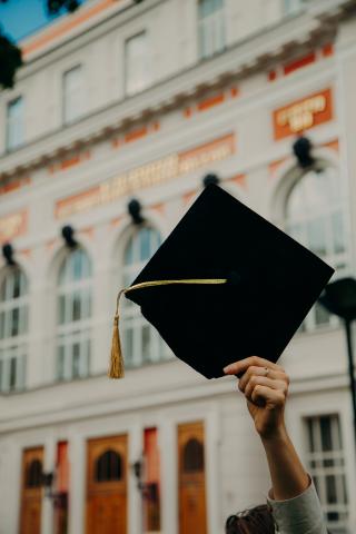 A graduate holding their cap in the air