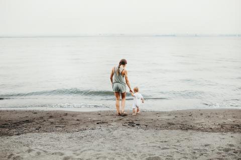 a person holding a child's hand at the beach