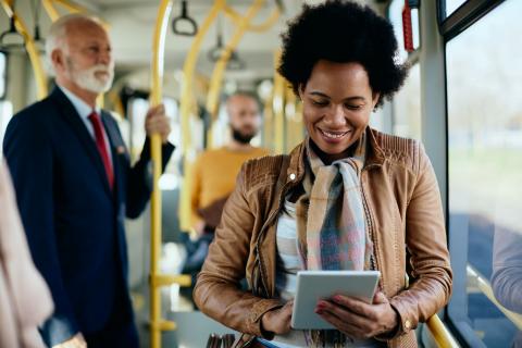 Woman riding the bus, reading on her tablet