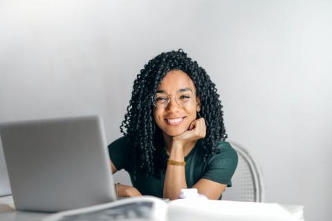 Image of a woman smiling in front of a laptop